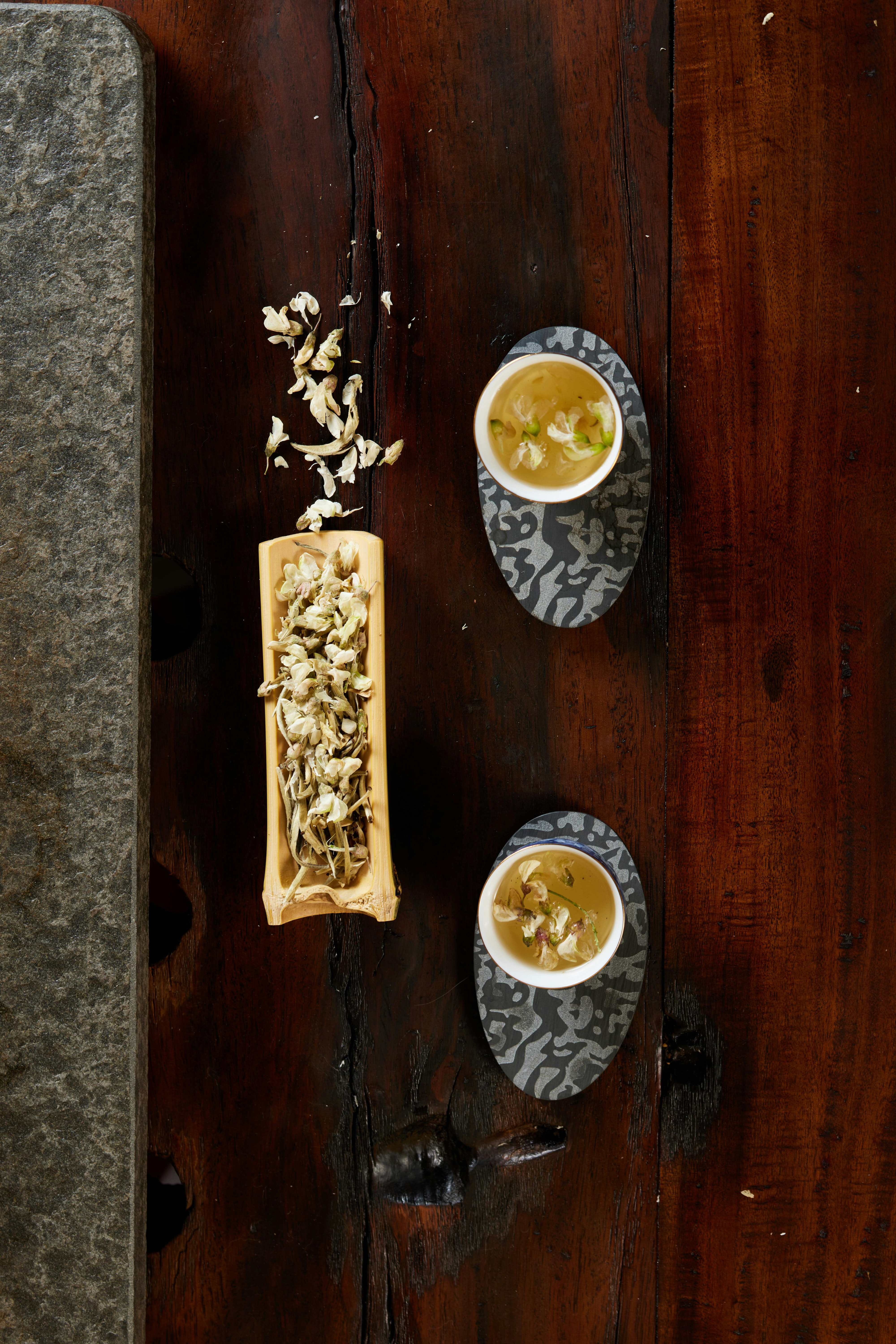 Tasses en porcelaine contenant une infusion de thé au jasmin, accompagnées de fleurs de jasmin fraîches